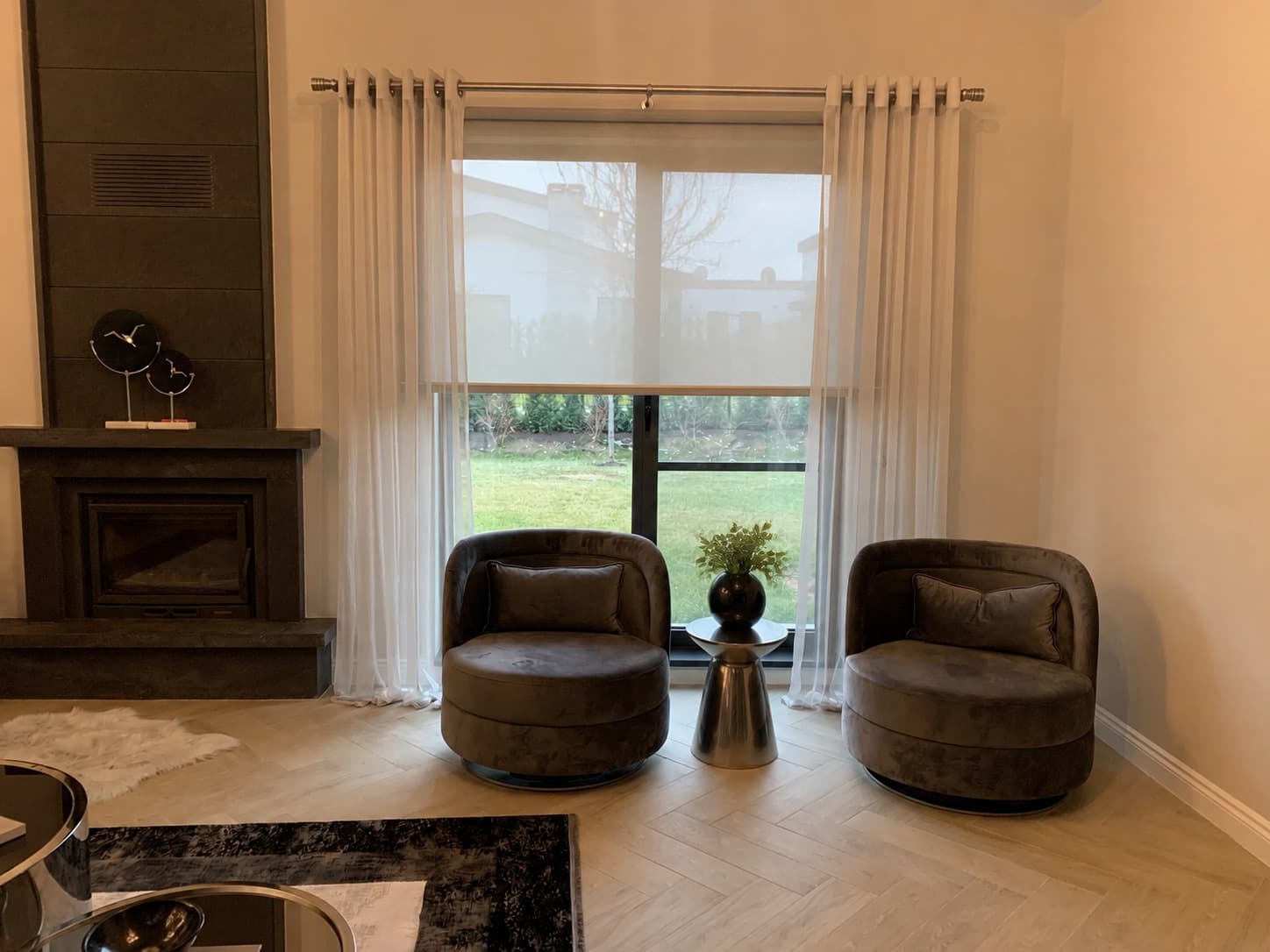 Villa Voga salonunda şömine yanındaki pencerede sunscreen stor ve kapsüllü tül perde
