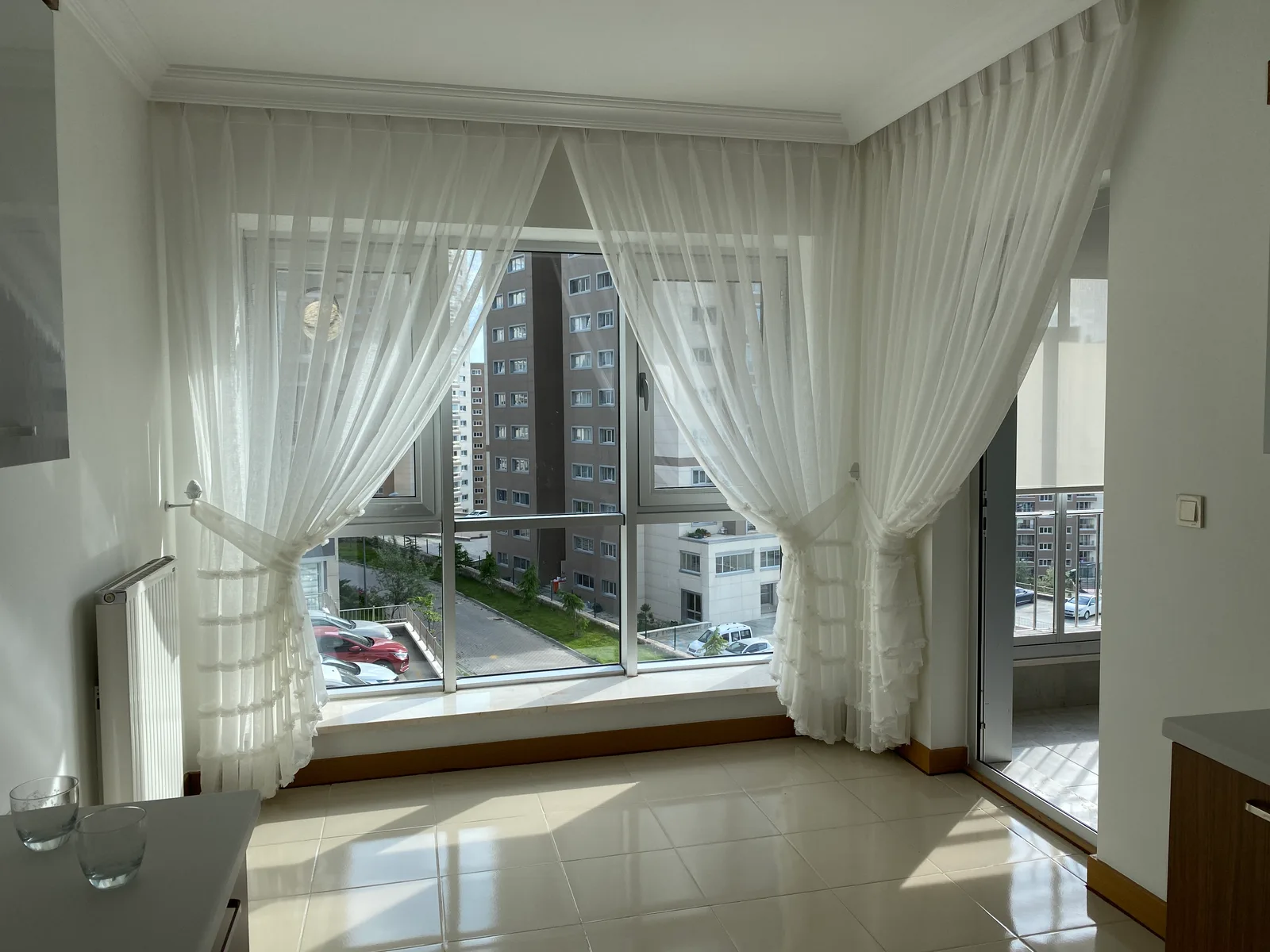 White sheer curtains on a wide window and balcony door in a dining area