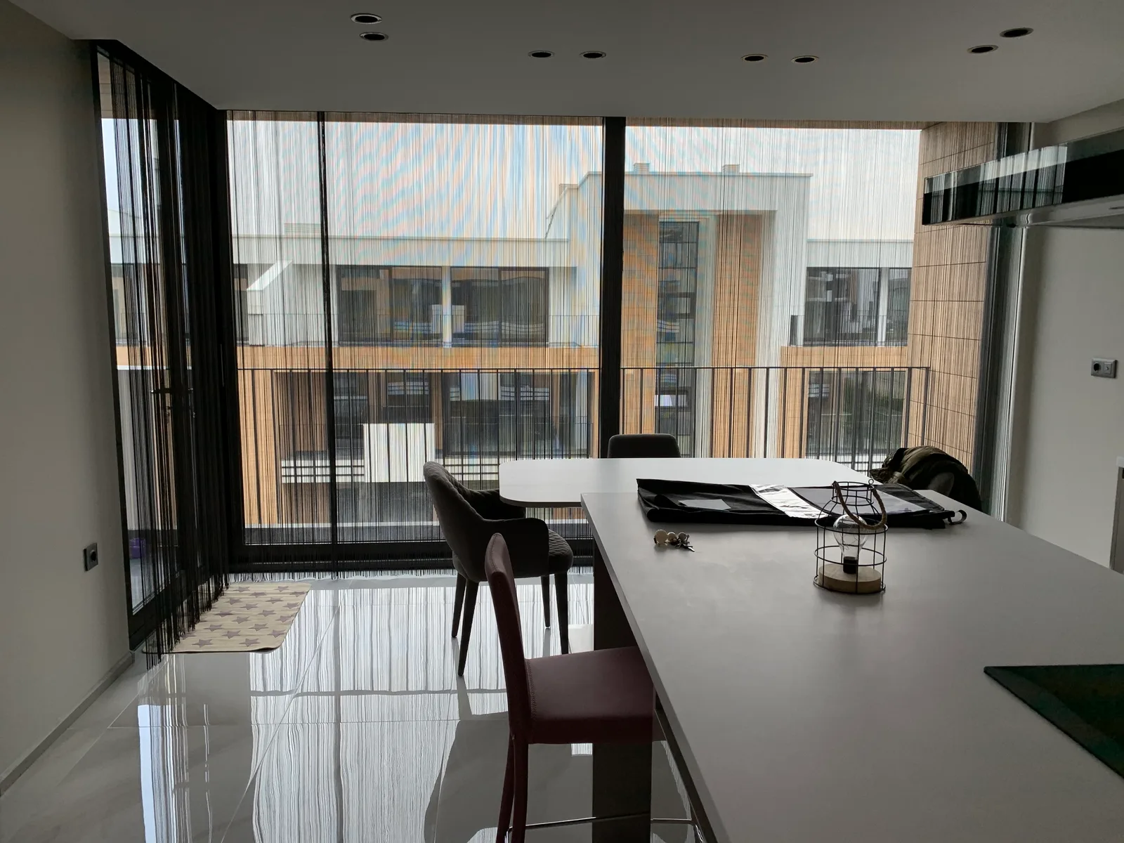 Black string curtains behind a kitchen island and dining table