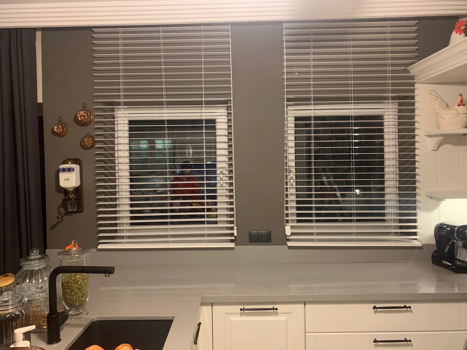 White Venetian blinds on two windows above a kitchen counter