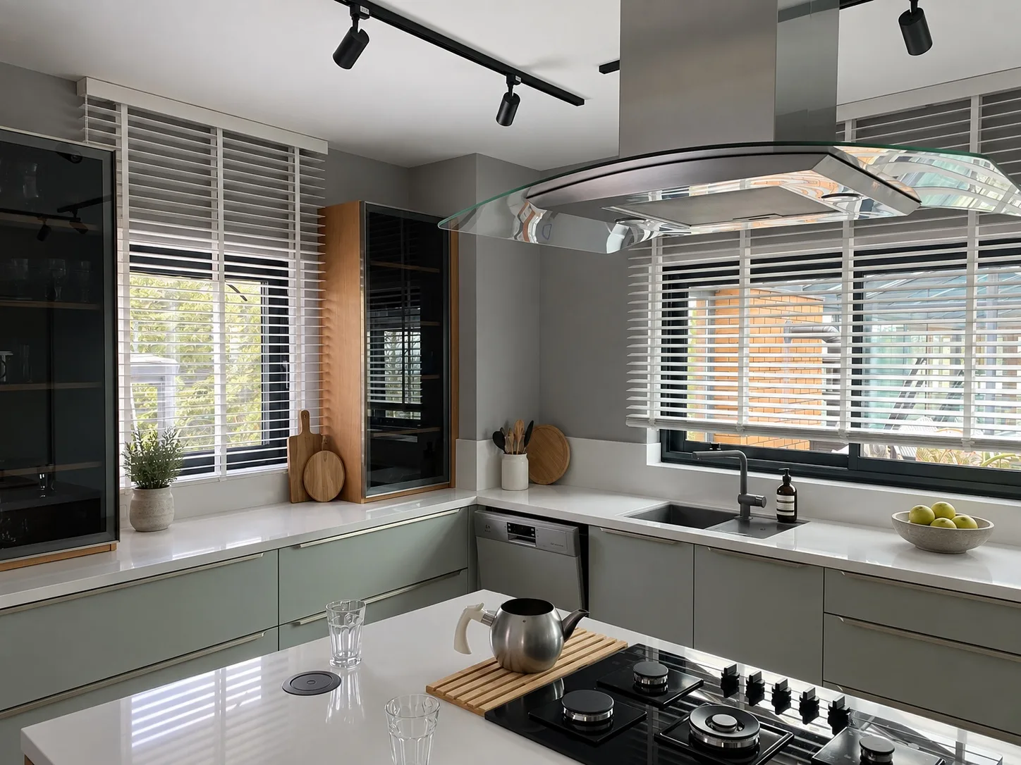 White wooden blinds on corner windows above a kitchen sink and counter