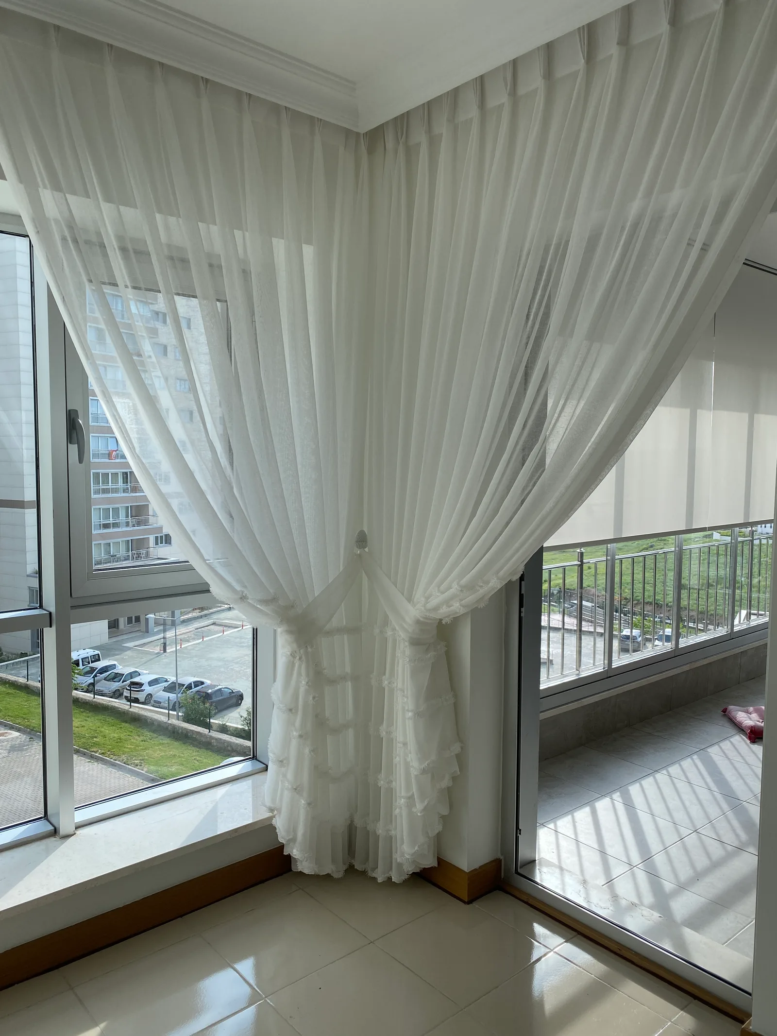 White sheer curtain tied back at the corner between a window and balcony door