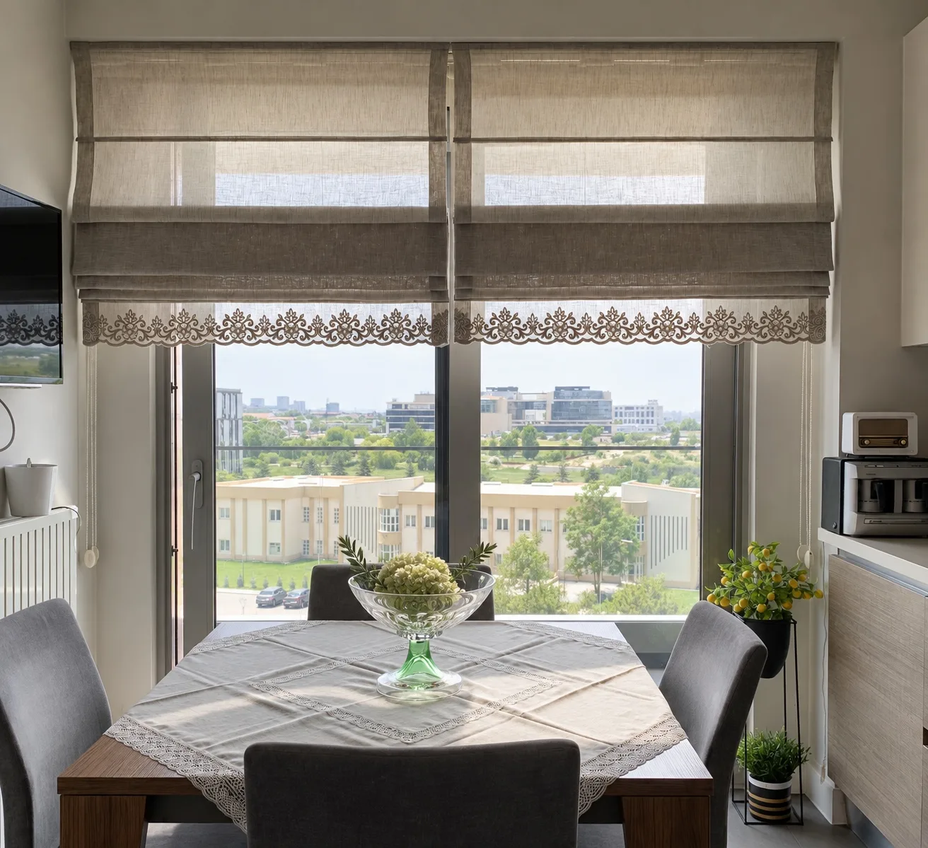 Beige Roman blinds with lace edging on a window behind a dining table
