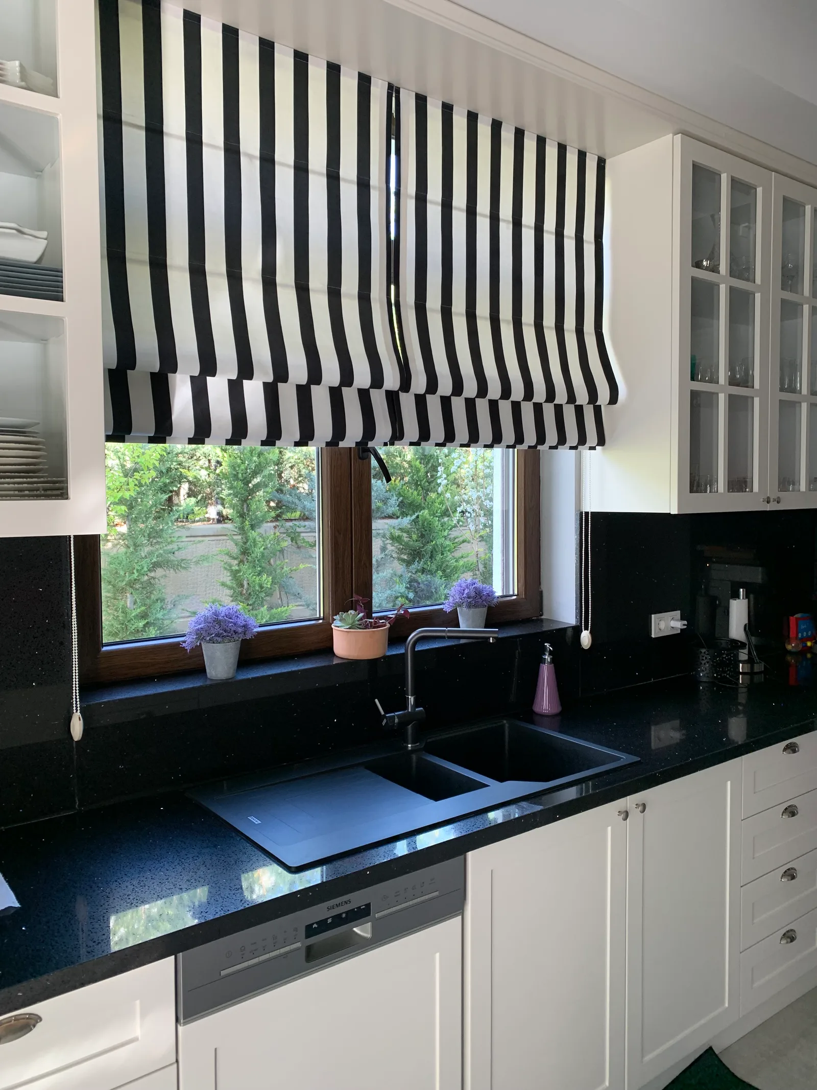 Black-and-white striped Roman blind on a window above a kitchen sink