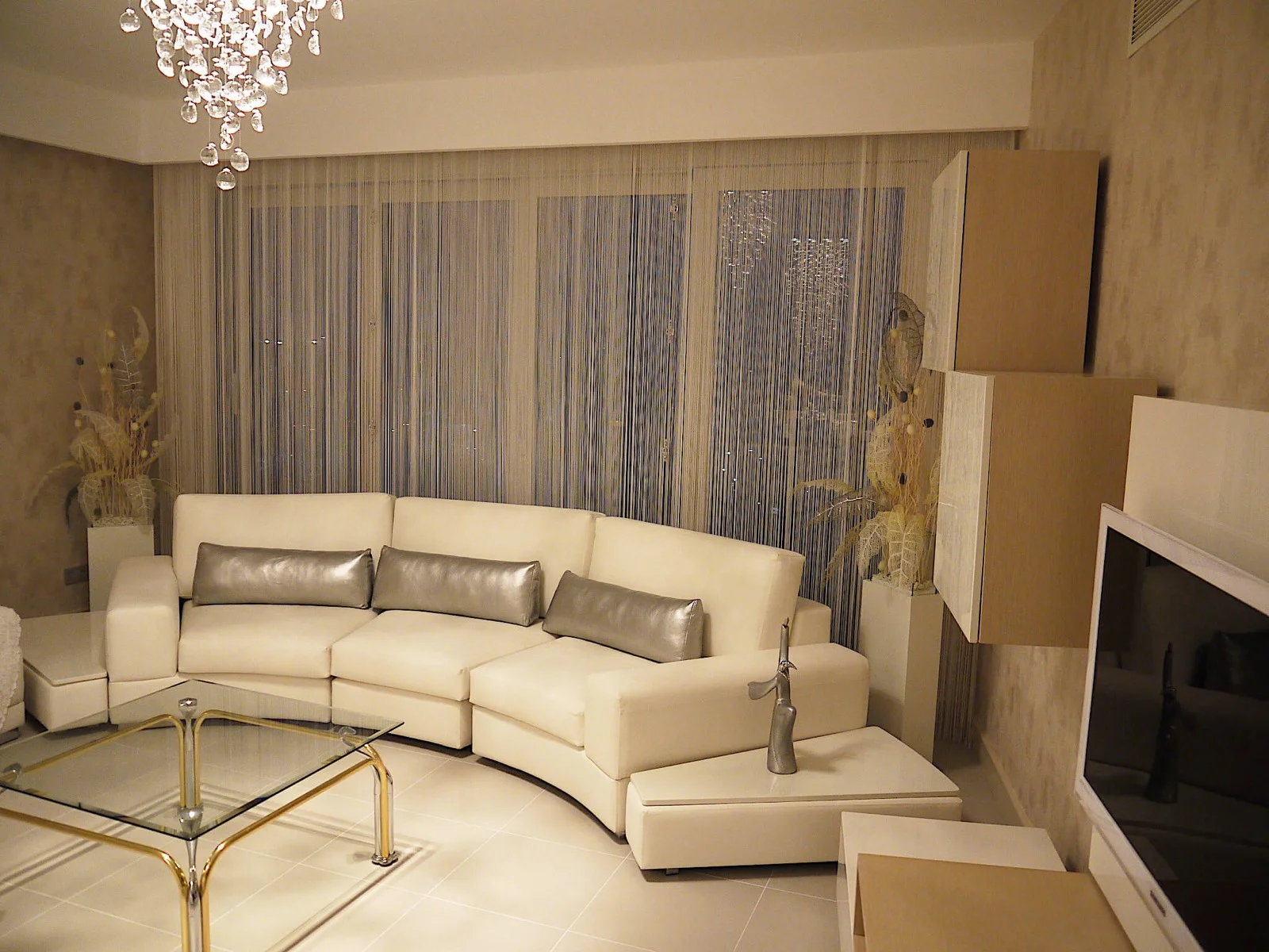 Light-coloured string curtains across wide living-room glazing