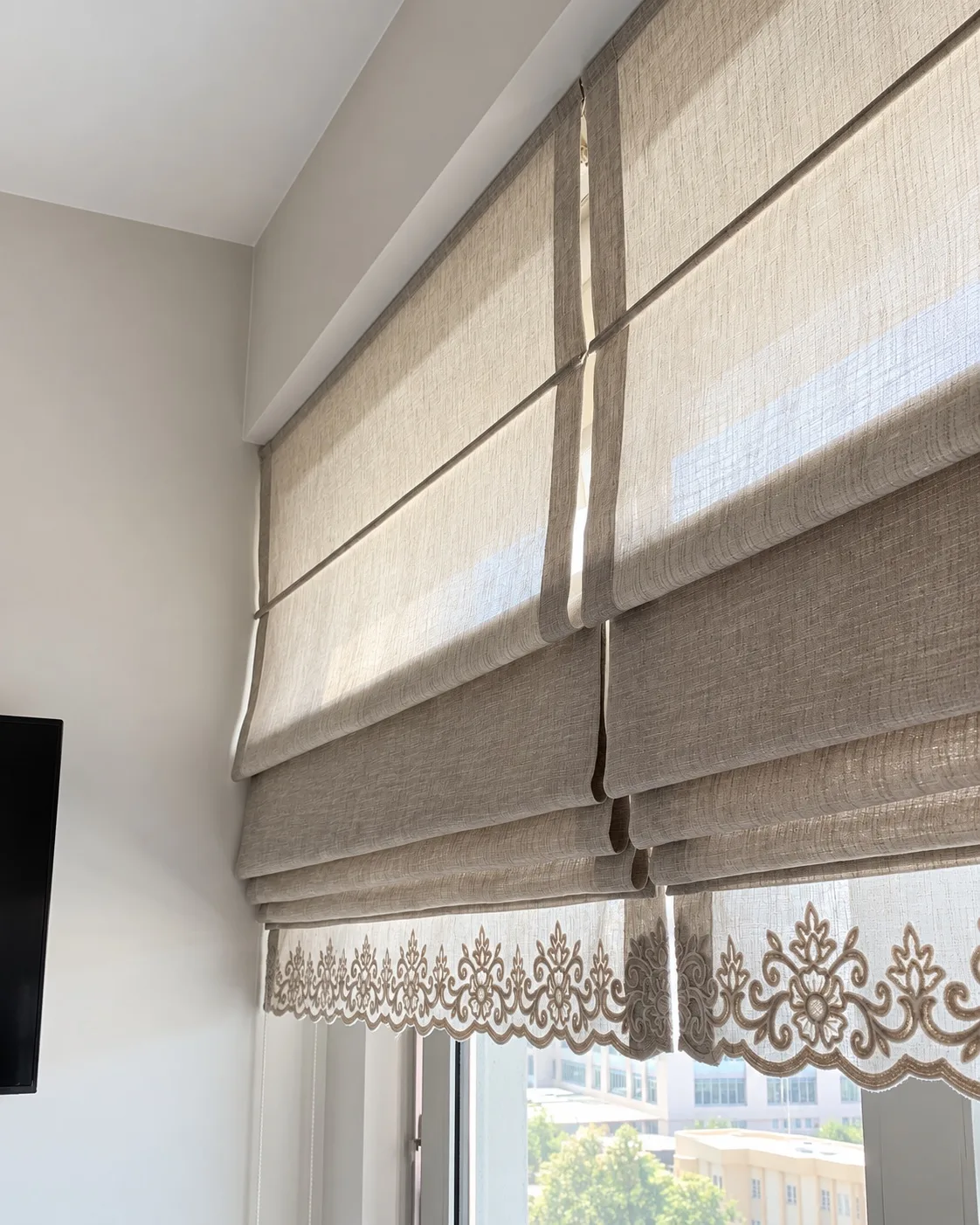 Close-up of fabric folds and lace edging on beige Roman blinds