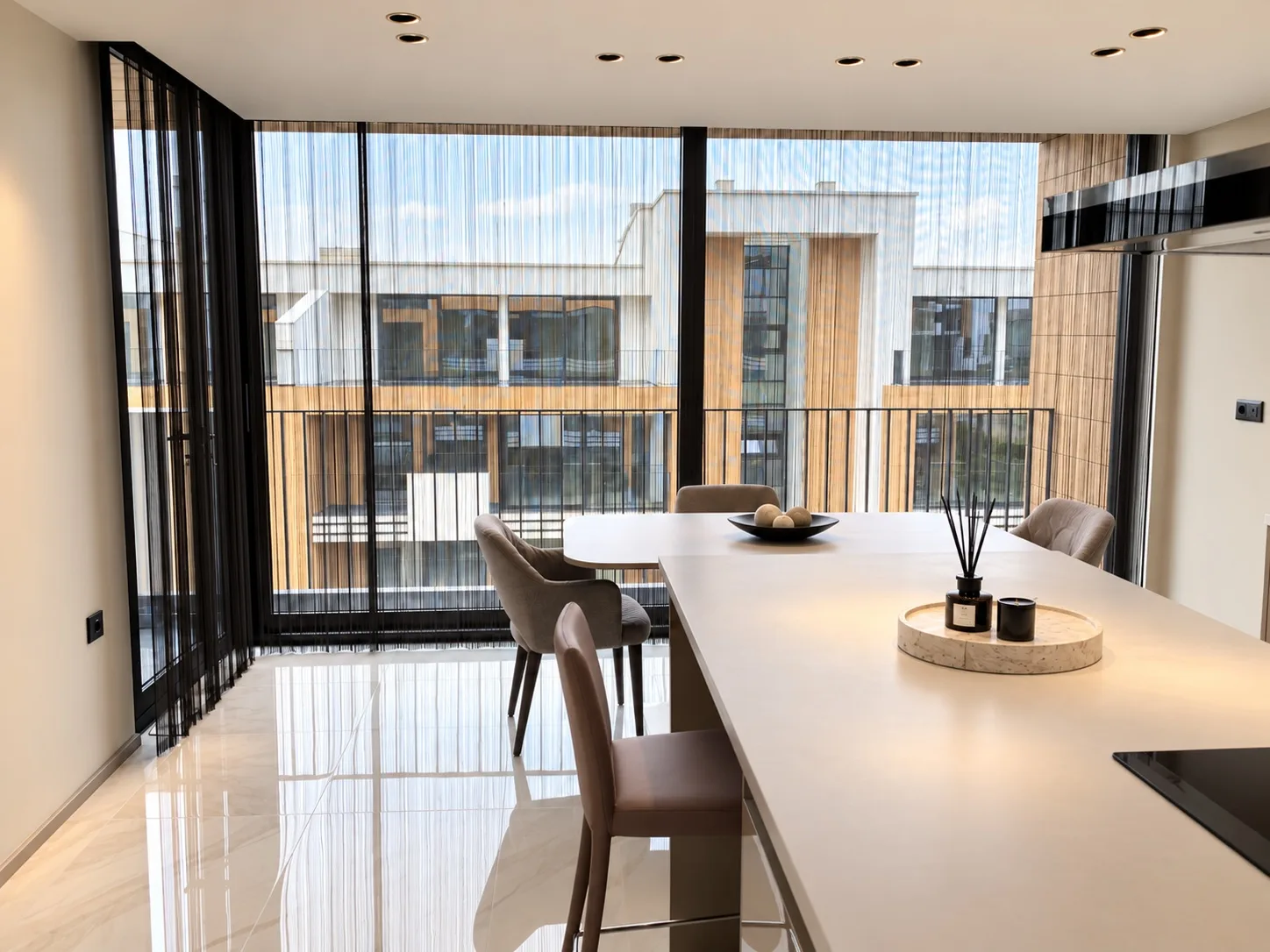 Black string curtains across large windows in a kitchen and dining area