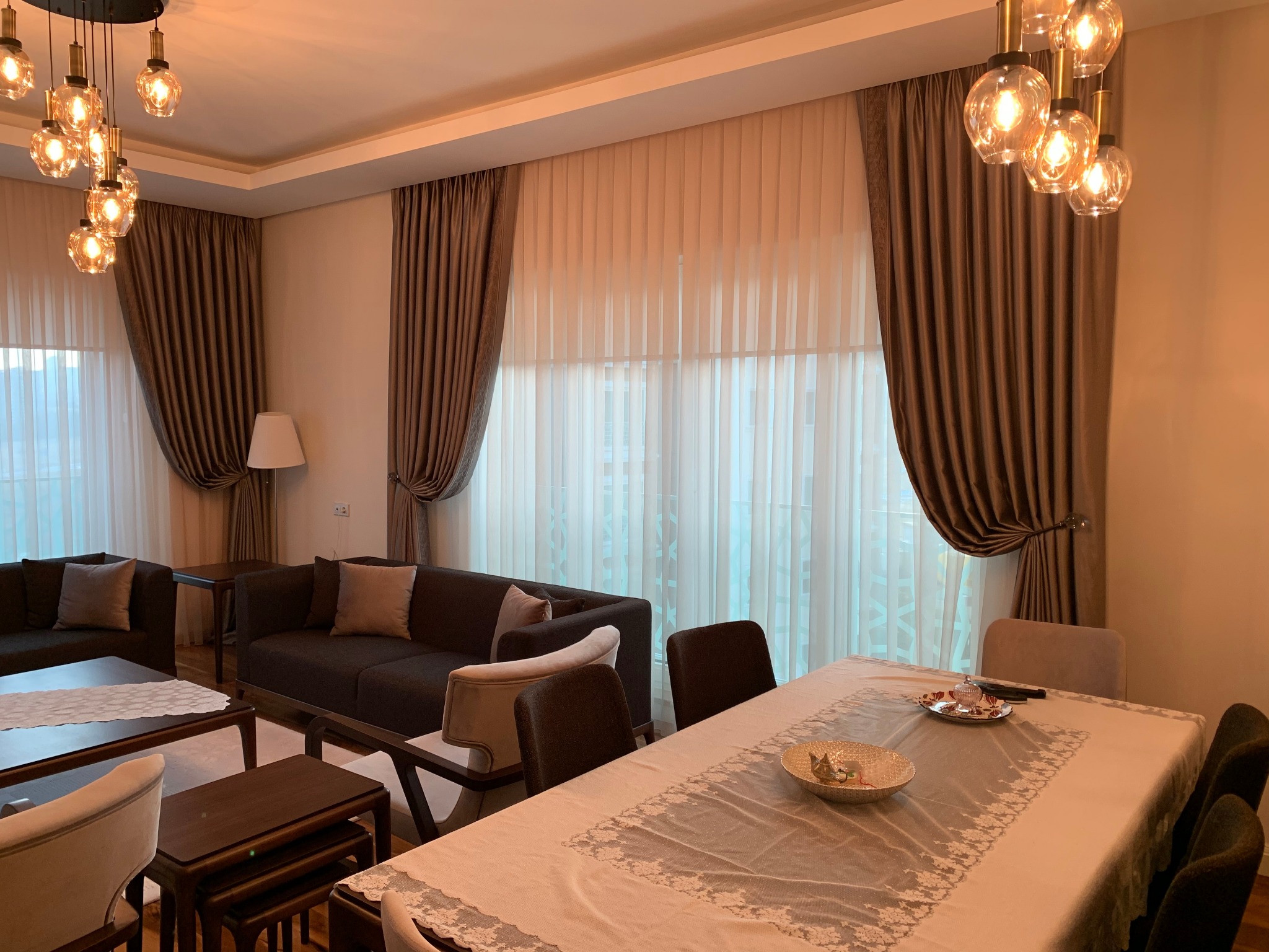Sofa Loca salonunun yemek alanından görülen cam cephesinde dökümlü tül ve fon perdeler