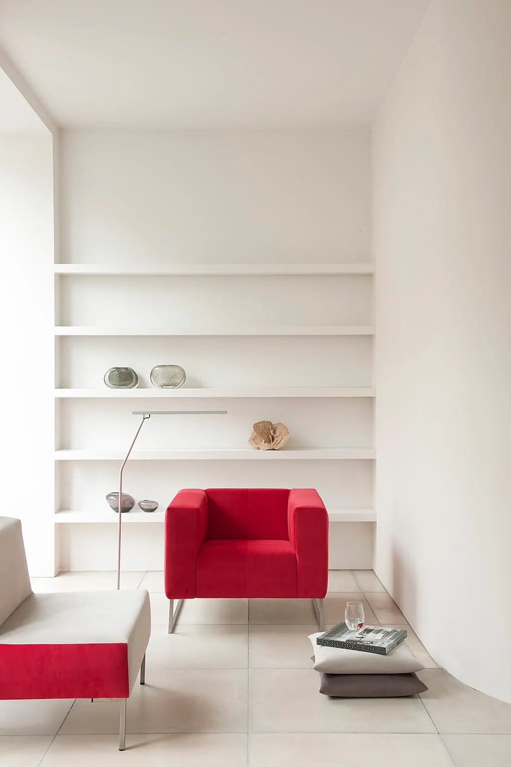 Minimal beyaz salonda kırmızı döşemeli tekli koltuk