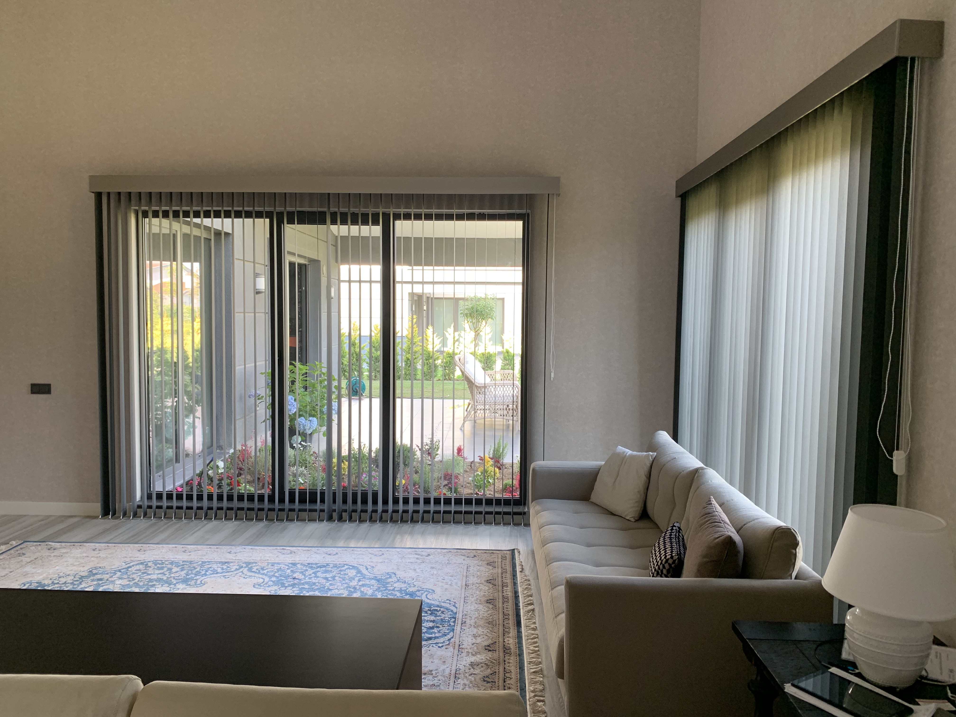 Villa Voga Gölbaşı salonunda iki geniş cam yüzeyi çevreleyen özel ölçü kumaş dikey perde sistemi