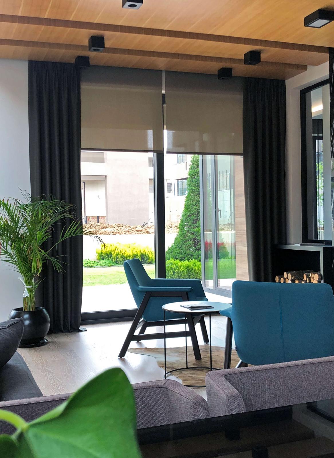 Dark curtains relate to upholstery, timber and glazing without exact matching.